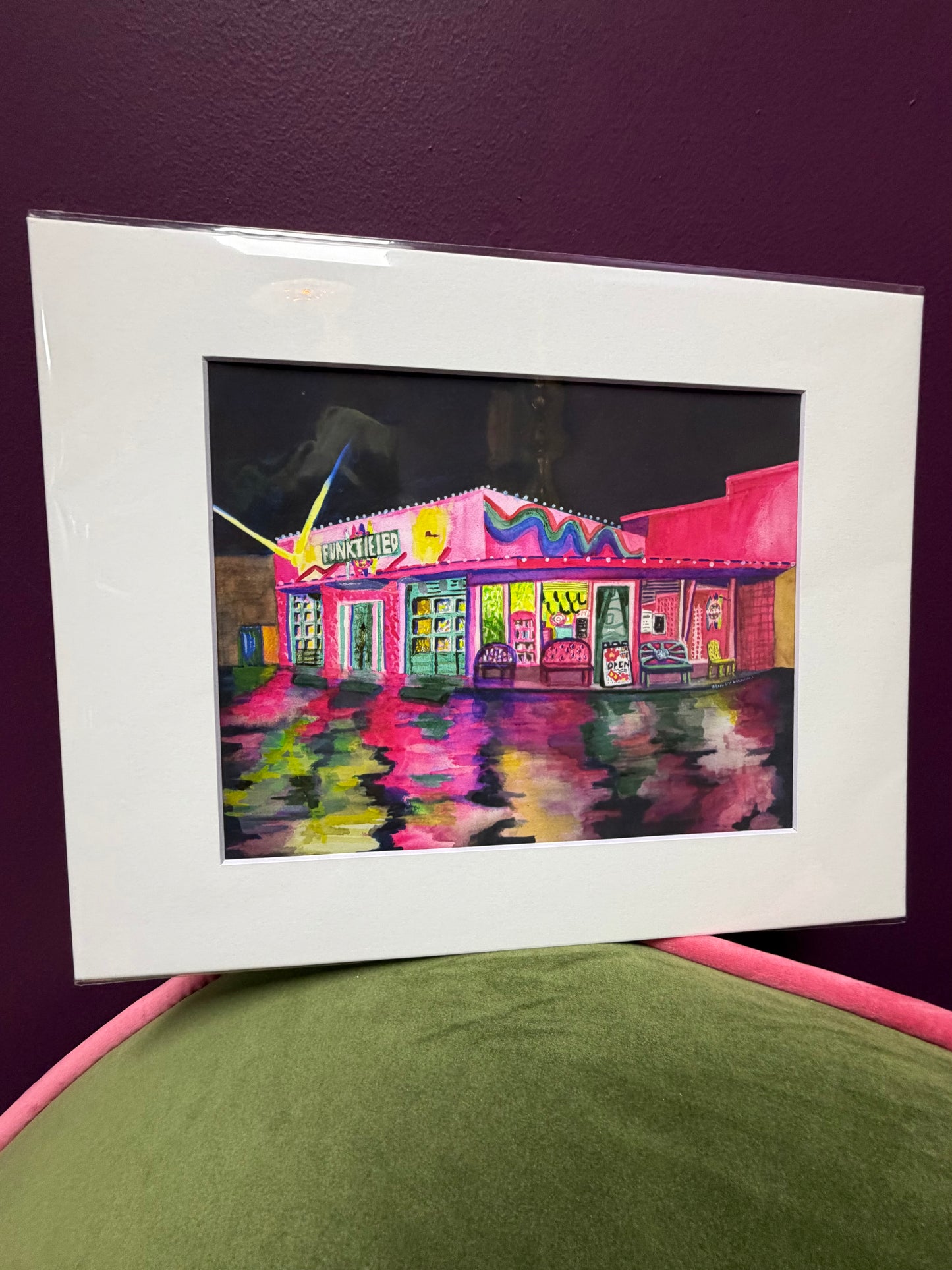 Framed artwork of a colorful building on a purple surface