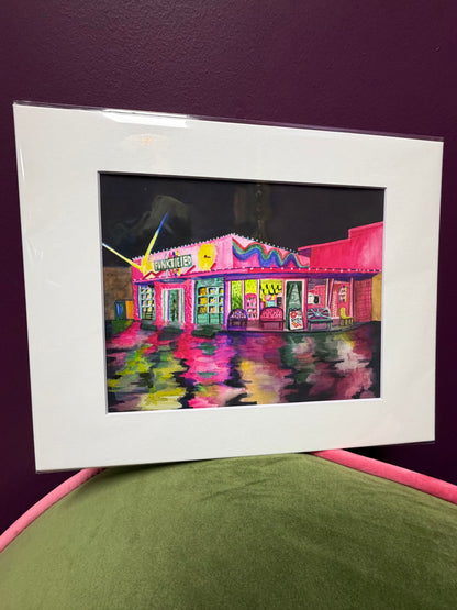 Framed artwork of a colorful building on a purple surface
