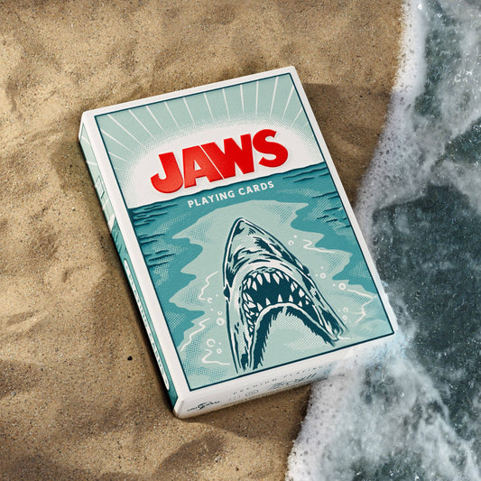 Jaws playing cards on a sandy surface with ocean waves