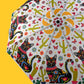 Colorful umbrella with black cat design on a yellow background