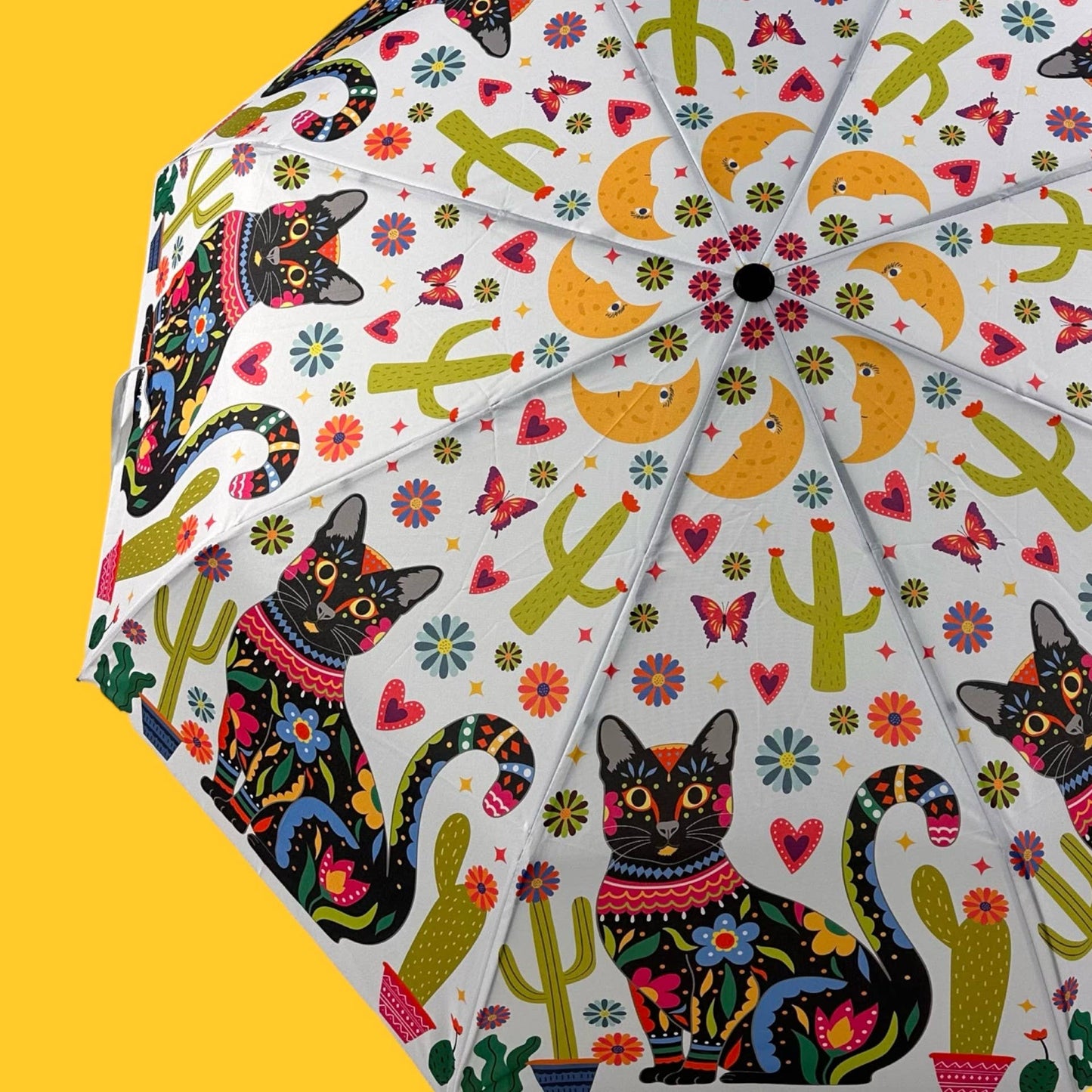 Colorful umbrella with black cat design on a yellow background