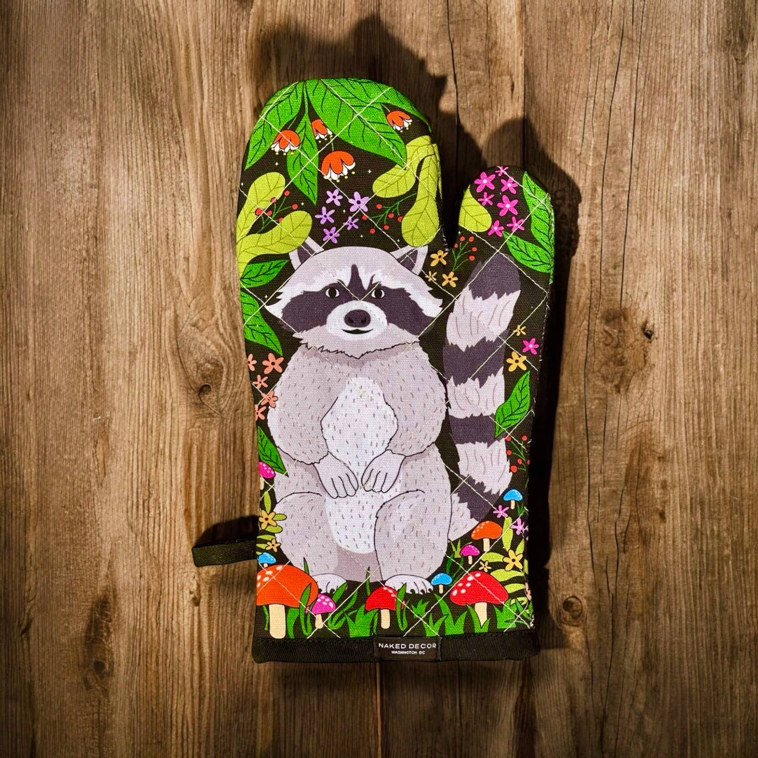 Colorful oven mitt with a raccoon design on a wooden background