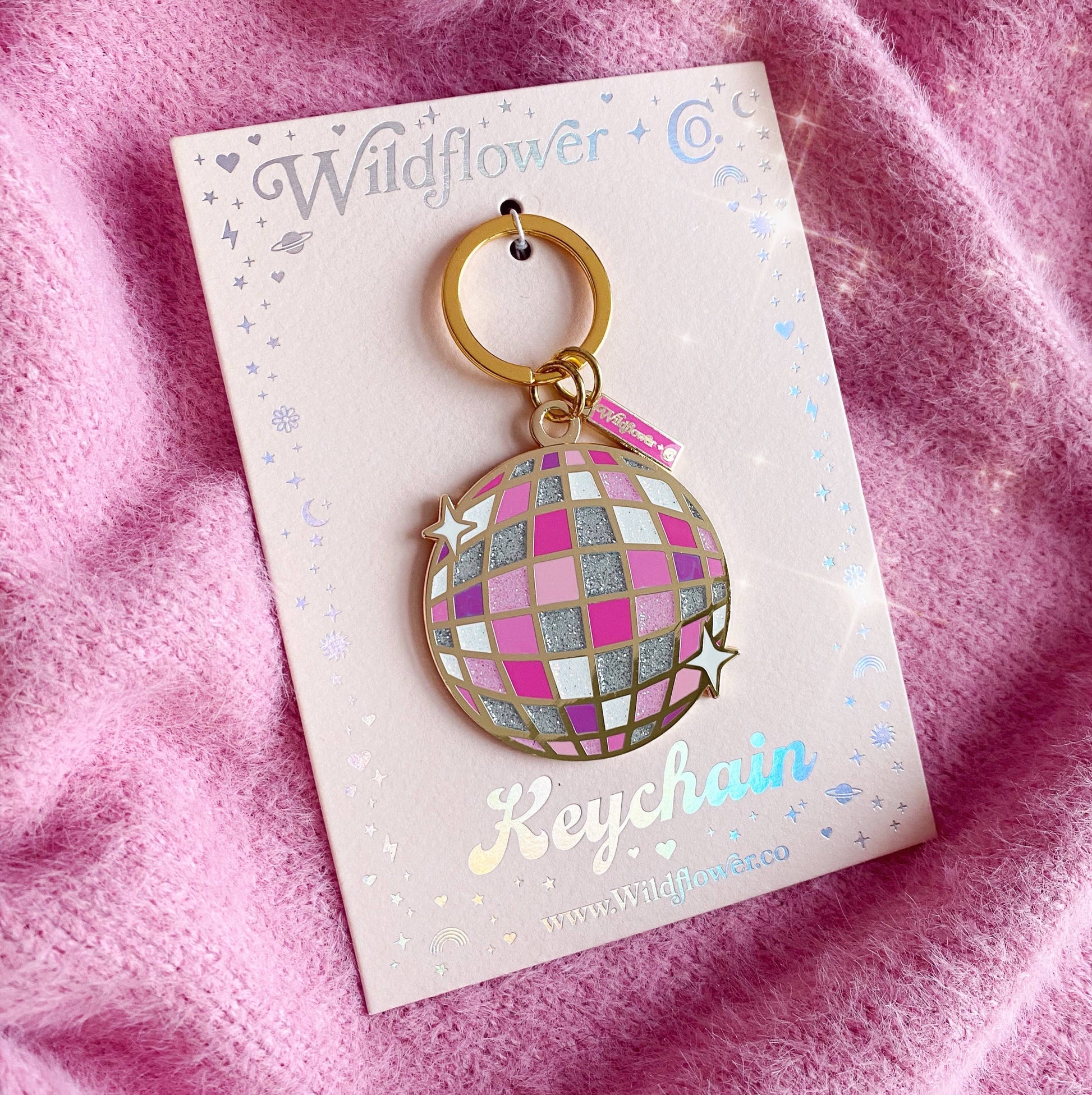 Keychain on Wildflower Co. packaging with pink and gold design against a pink fabric background