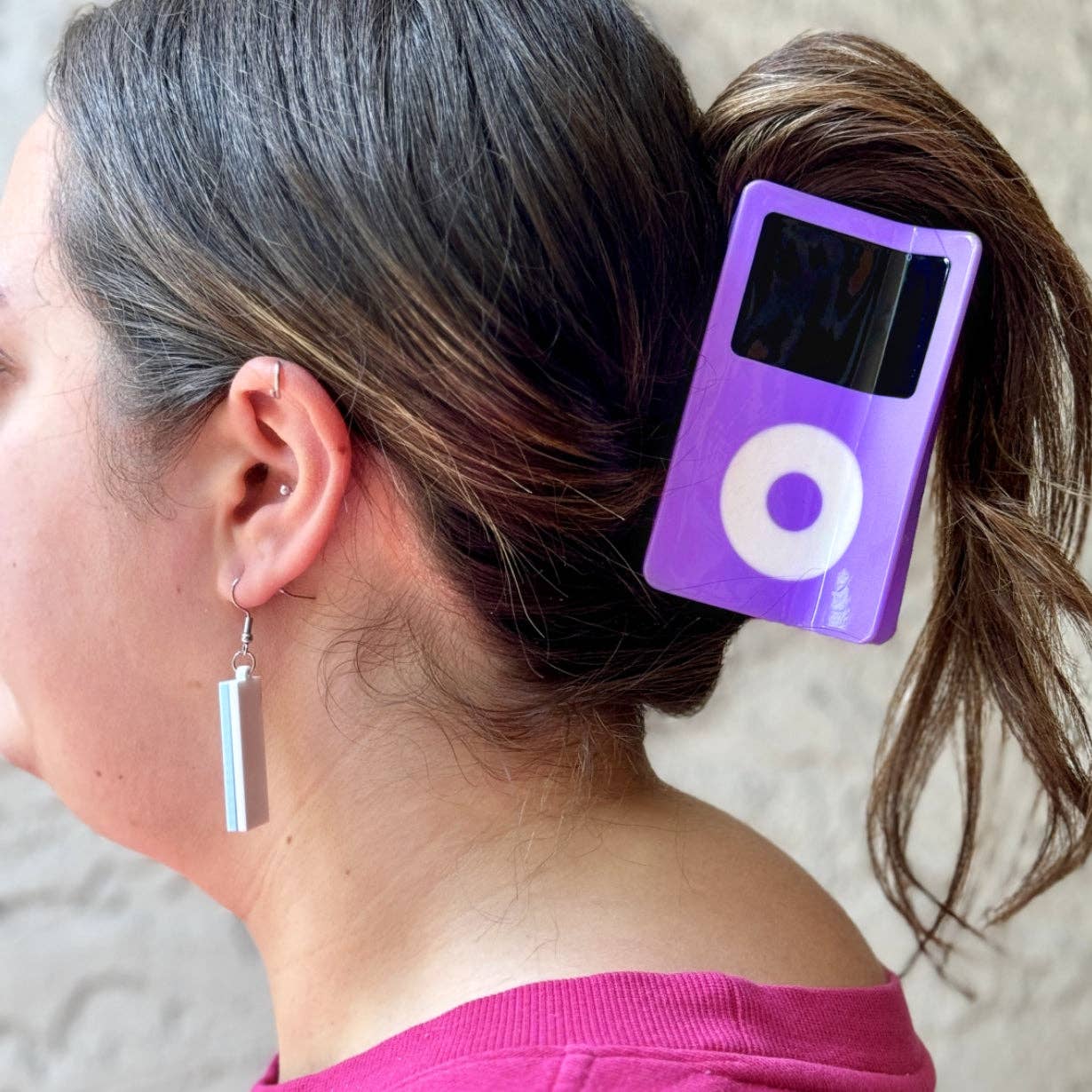Purple MP3 player-shaped hair clip on a person's hair with a neutral background