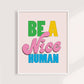 Framed poster with colorful text 'Be a Nice Human' on a light pink background