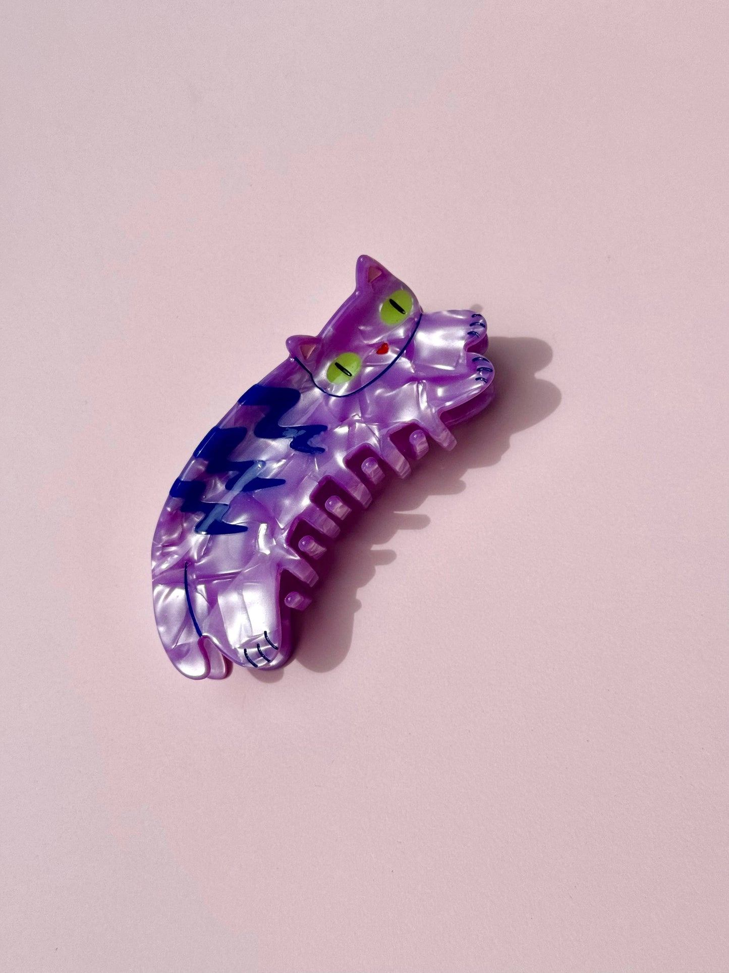 Colorful cat-shaped hair clip on a pink background