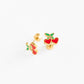 Pair of gold earrings with red heart and green leaf designs on a white background