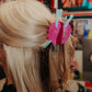 Person with pink knitting yarn hair clip in hair against a colorful background