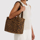 Person holding a leopard print tote bag against a white background