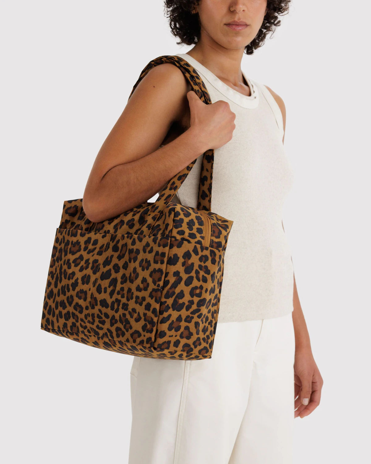 Person holding a leopard print tote bag against a white background