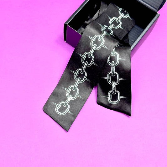 Black silk tie with chain design on a pink background
