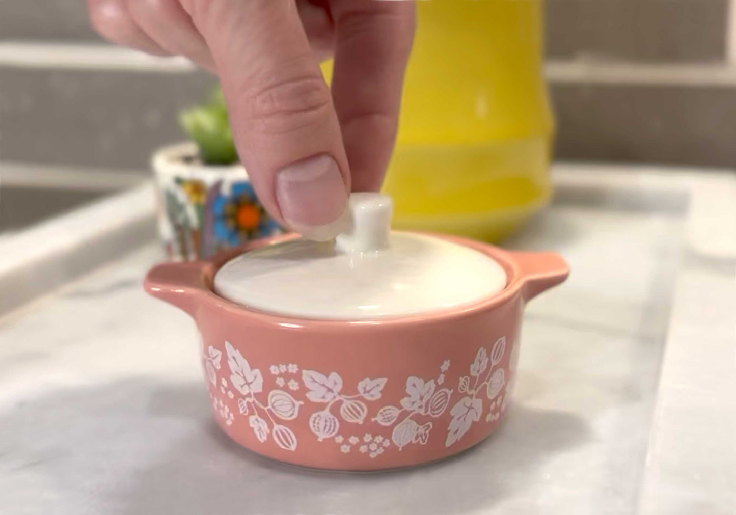 Pink pyrex ceramic container with floral patterns on a white surface