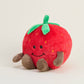 Plush strawberry toy with a smiley face on a light gray background