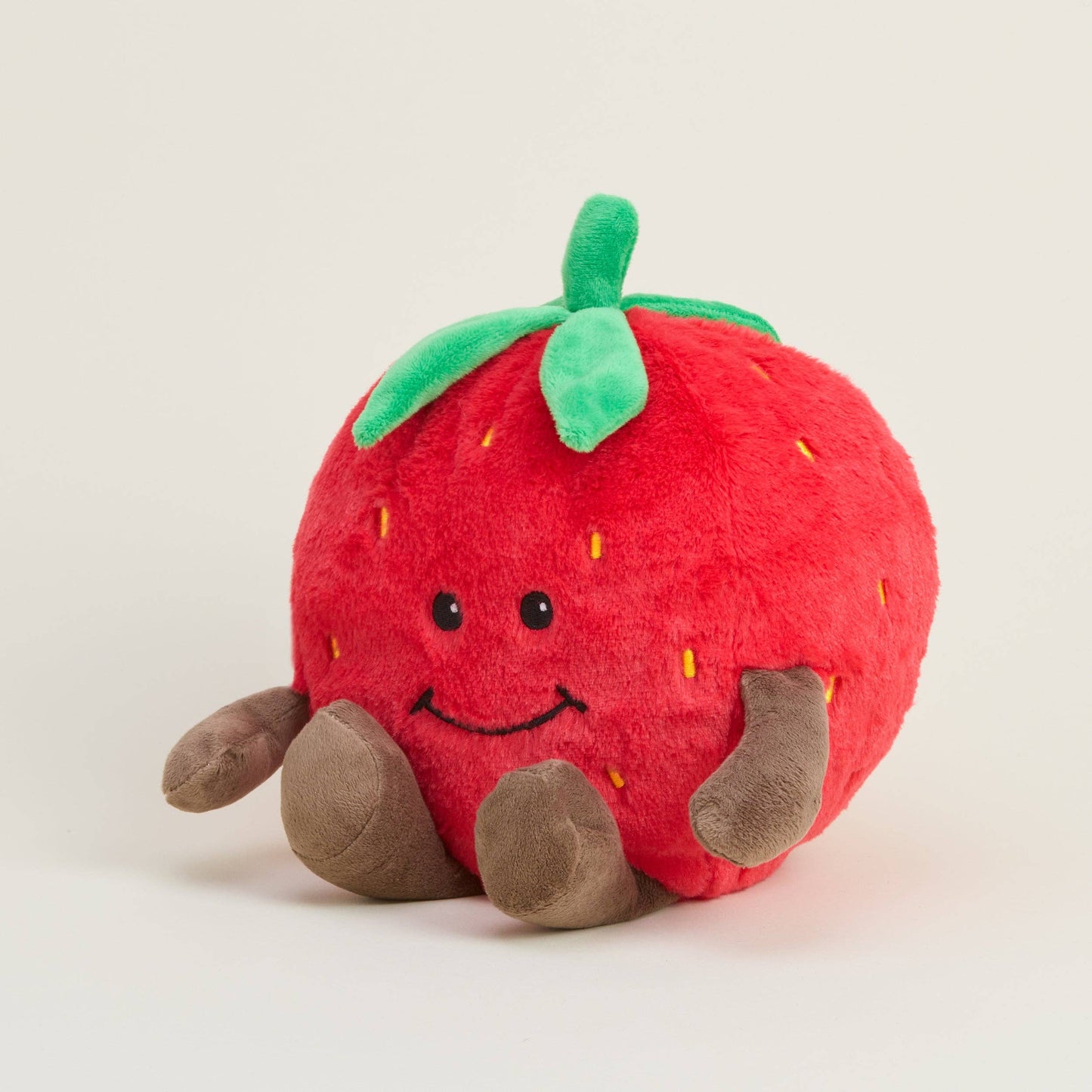 Plush strawberry toy with a smiley face on a light gray background