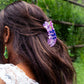 Person with a purple hair clip in their hair outdoors