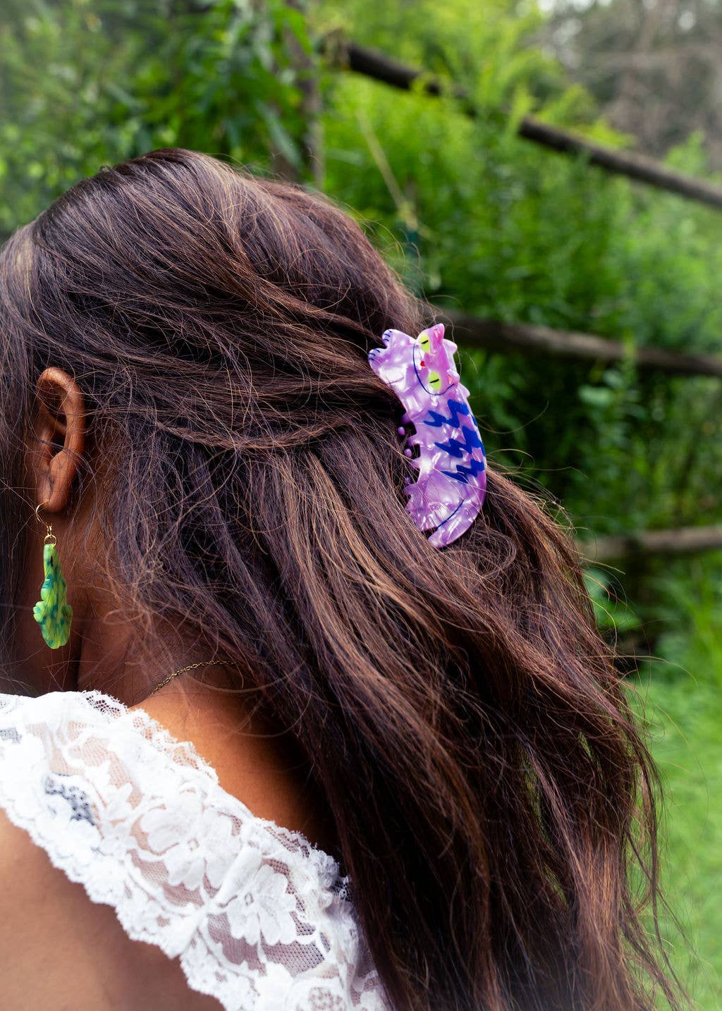 Person with a purple hair clip in their hair outdoors