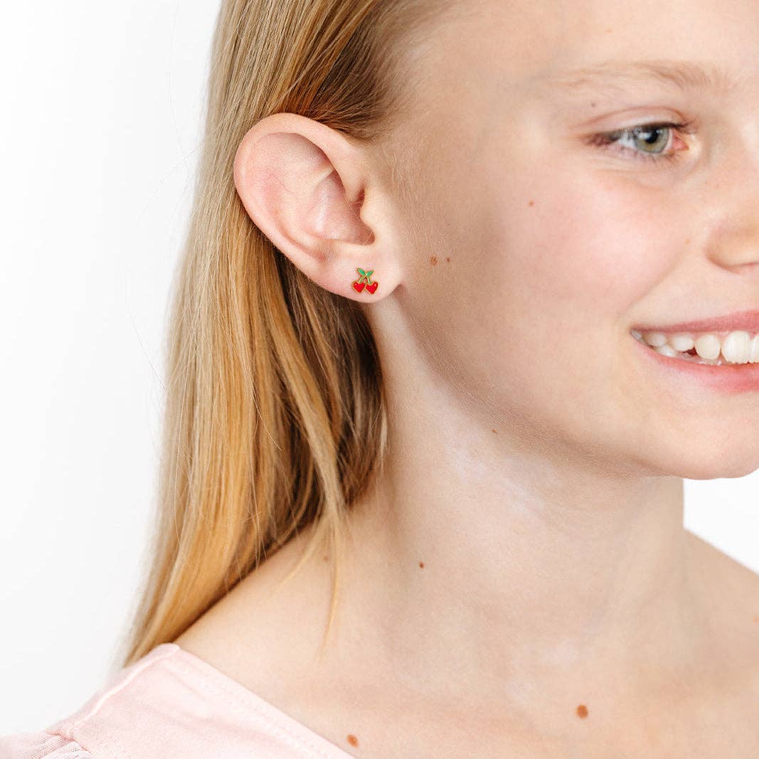 Close-up of a girl wearing a cherry stud earring on a white background
