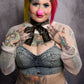 Person with colorful hair and tattoos wearing a denim outfit against a gray background