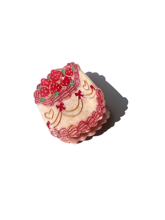 Decorative cake hair claw with red and pink icing on a white background