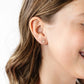 Close-up of a person wearing a floral earring with a plain background