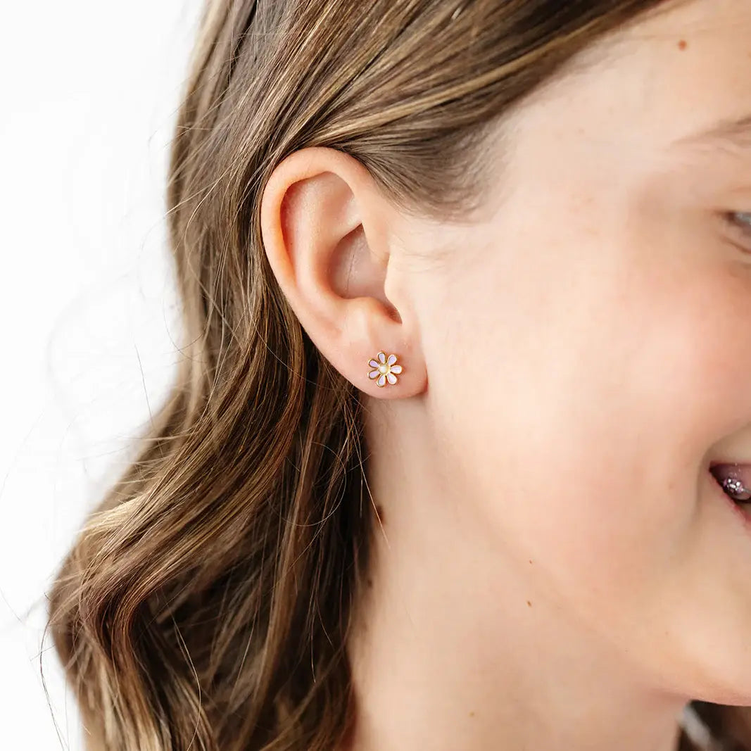 Close-up of a person wearing a floral earring with a plain background