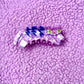 Cat-shaped hair clip with blue and white stripes on a purple textured background