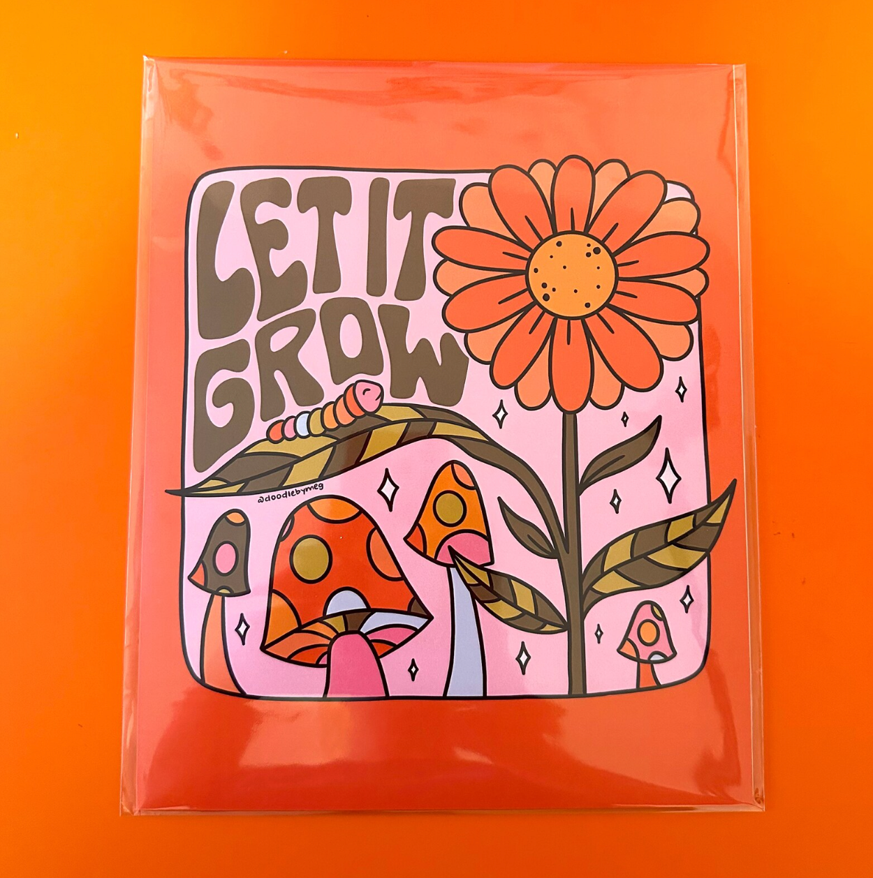 A print with a floral design and 'Let It Grow' text on an orange background