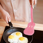 Person cooking eggs in a pan with a pink guitar spatula.