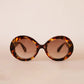 Tortoiseshell sunglasses with brown lenses on a beige background