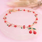 Bracelet with red and green cherry beads on a pink surface