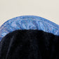 Close-up of a black stuffed animal with blue sparkles on a light gray background