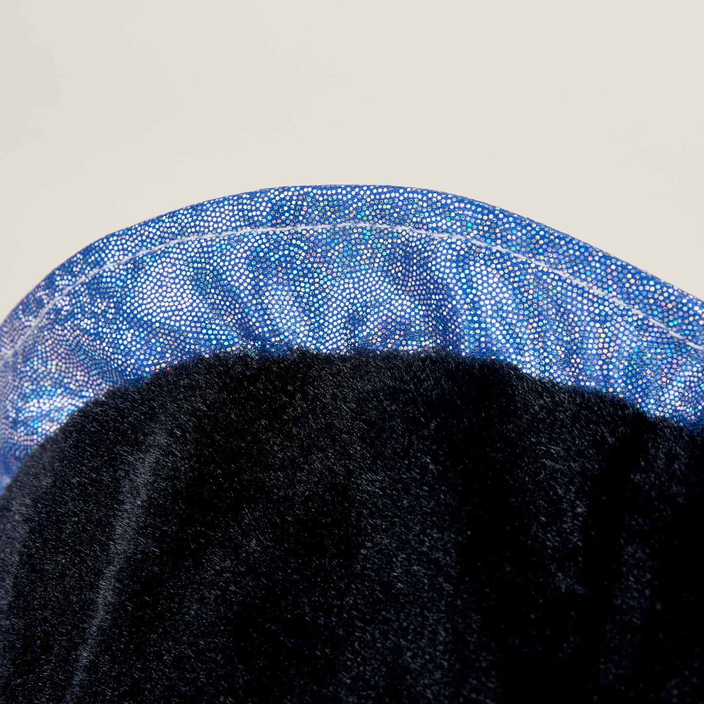 Close-up of a black stuffed animal with blue sparkles on a light gray background