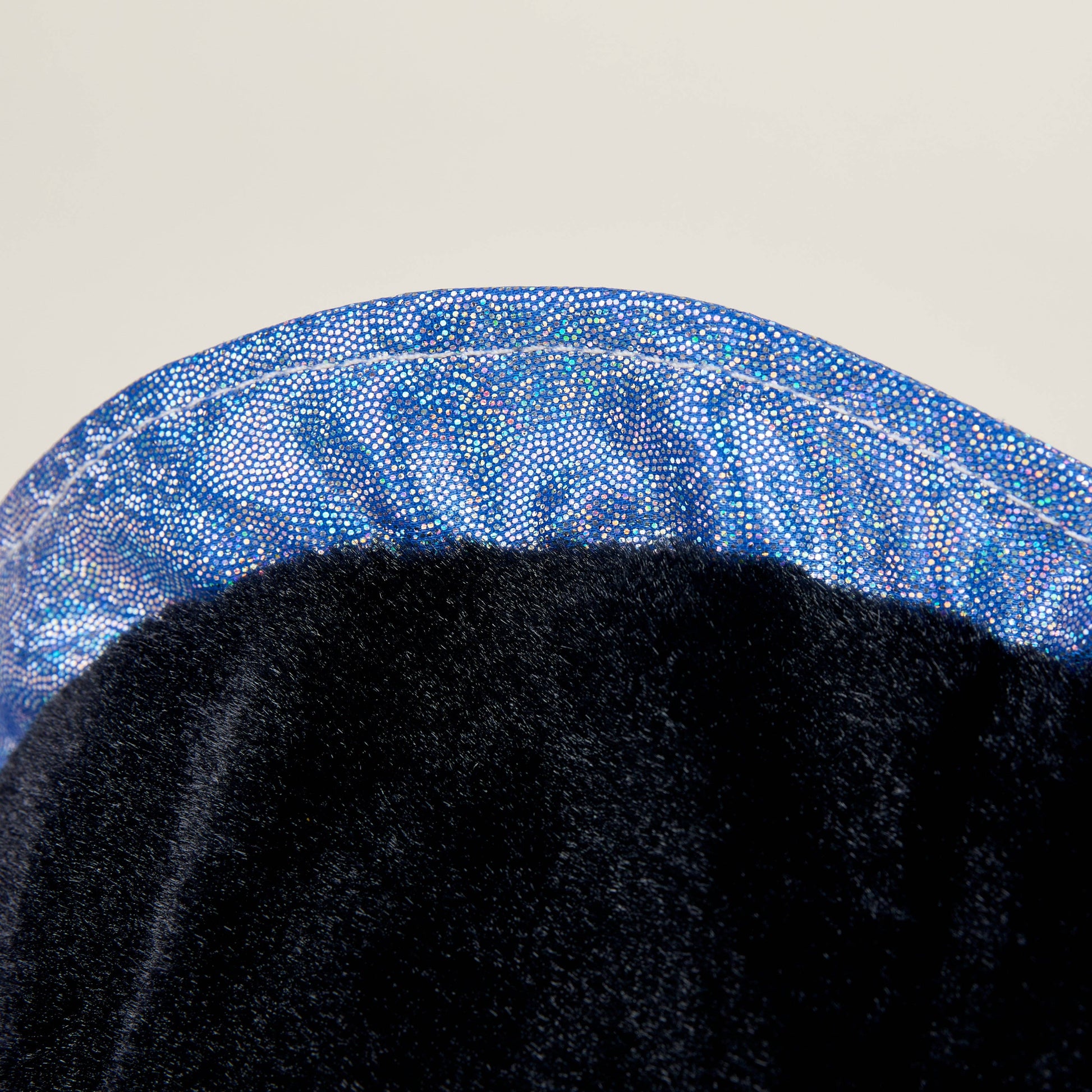Close-up of a black stuffed animal with blue sparkles on a light gray background