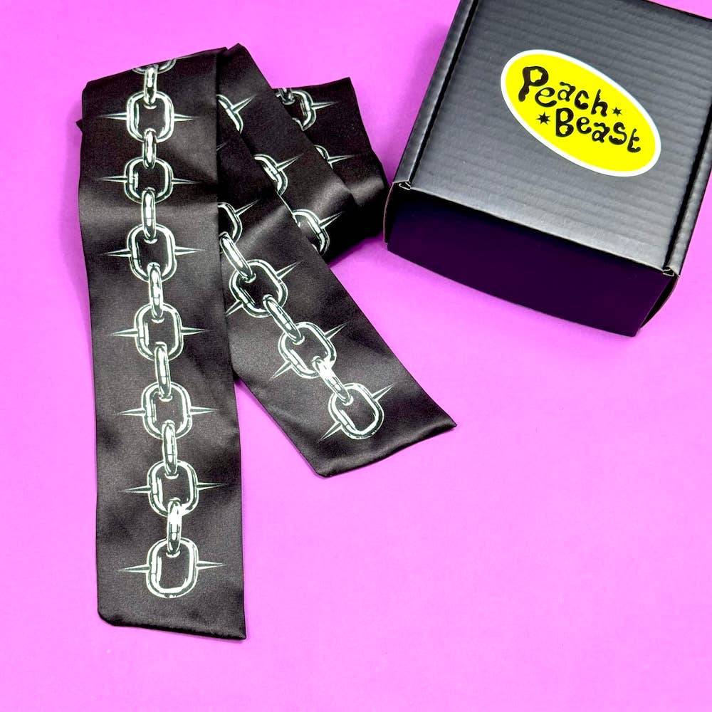 Black satin scarf with chain design next to a box labeled 'Peach Beast' on a pink background