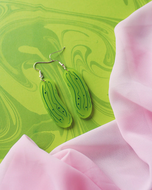 Green marbled earrings on a green and pink fabric background