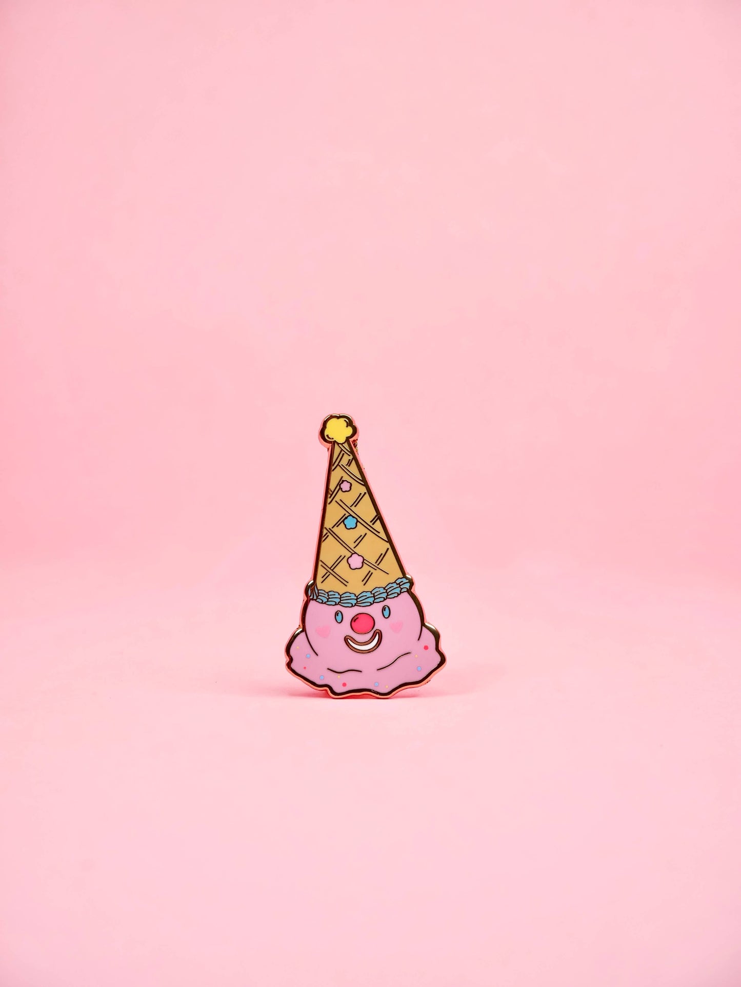 Pink clown figurine with a yellow party hat on a pink background