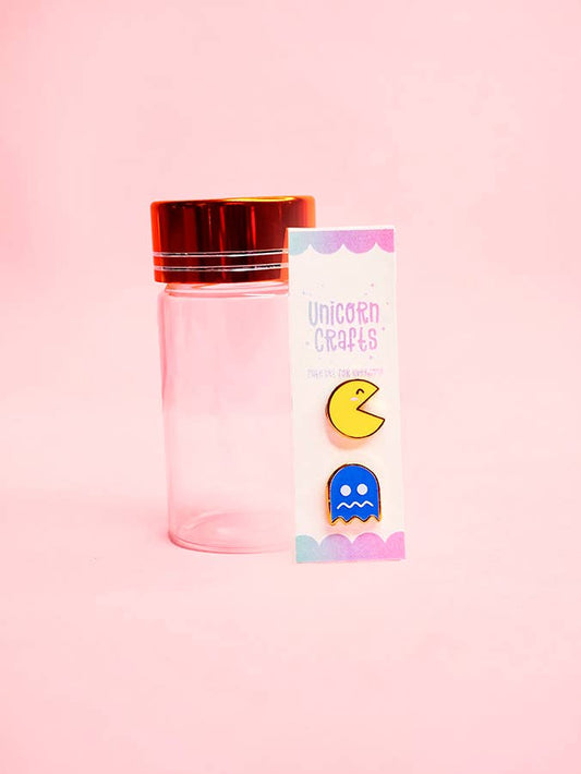 pac man and ghost earrings with glass bottle on a pink background