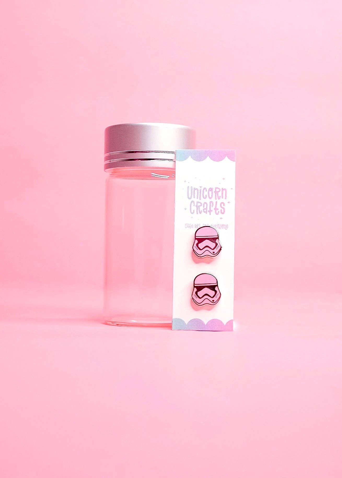  a small card featuring pink stormtrooper earrings on a pink background