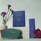 Books titled 'Planet Grief' and 'The Book of Shadows' with flowers on a white surface.