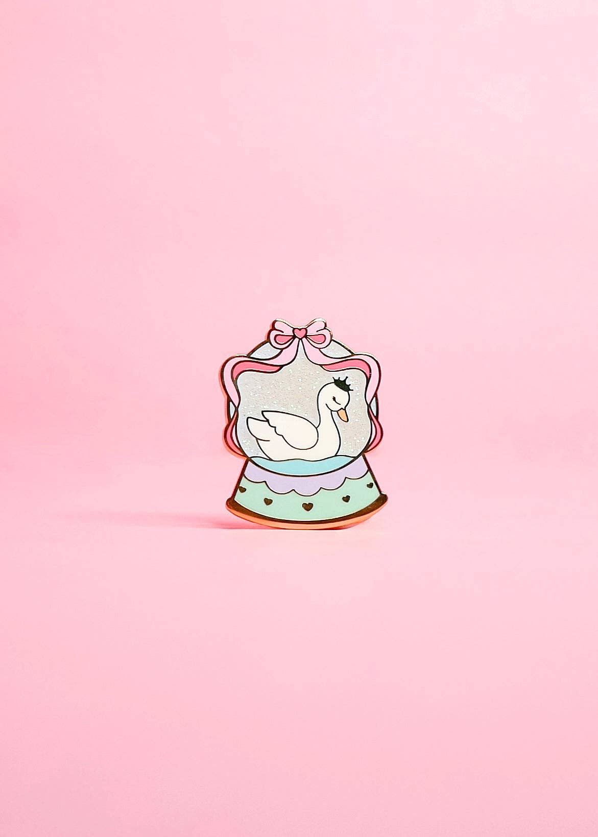 Decorative pin with a swan design on a pink background